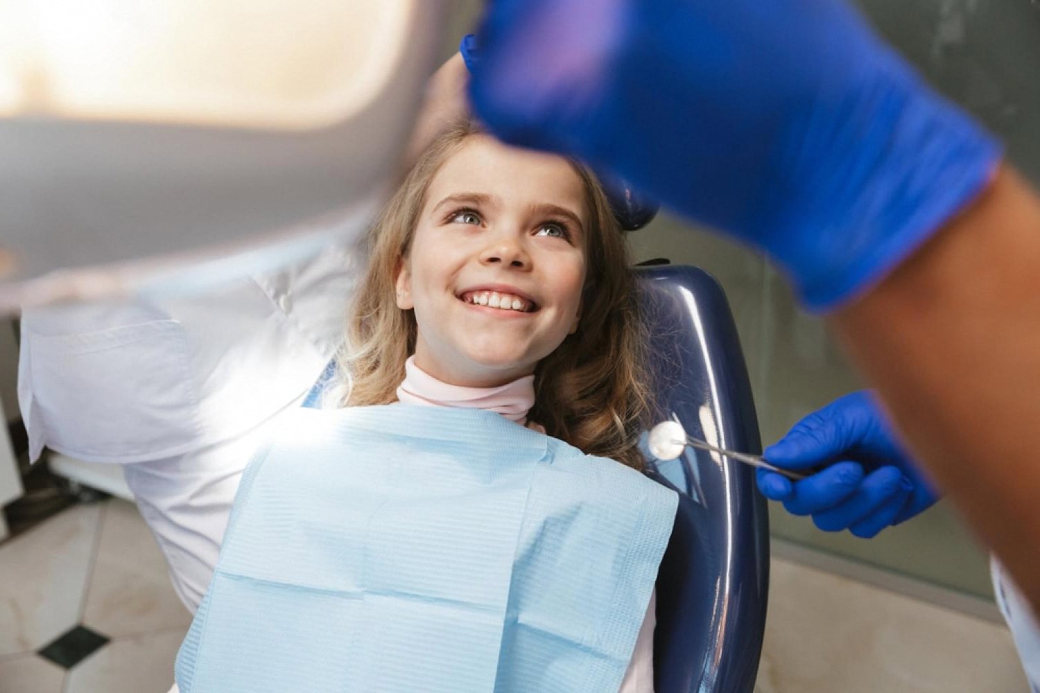 Young girl smiling in a dental chair during her first orthodontic check-up