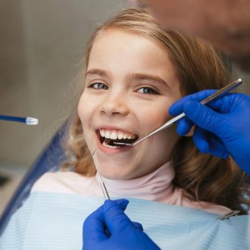 Child having her teeth examined by an orthodontist with dental tools