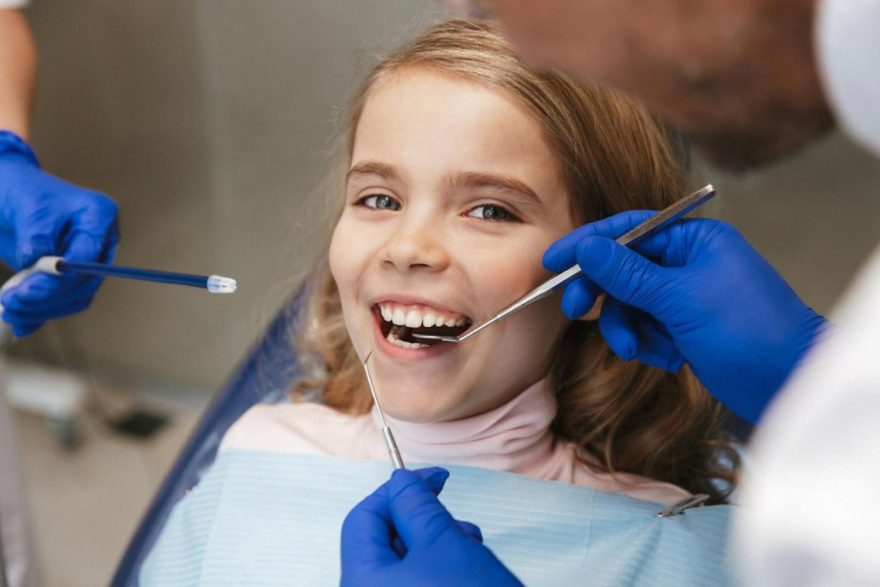 Child having her teeth examined by an orthodontist with dental tools
