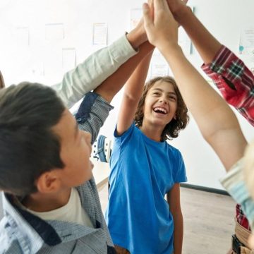 Group of primary school classmates giving a high five after a team activity