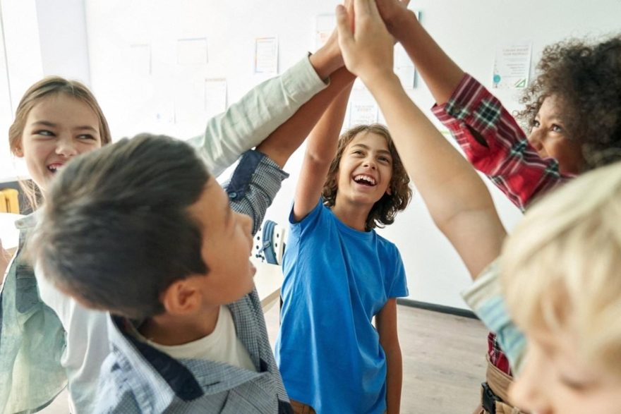 Group of primary school classmates giving a high five after a team activity
