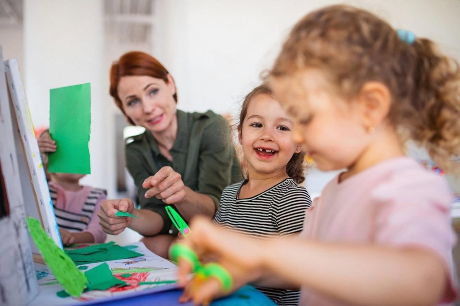 Young children collaborating on an art project with their teacher