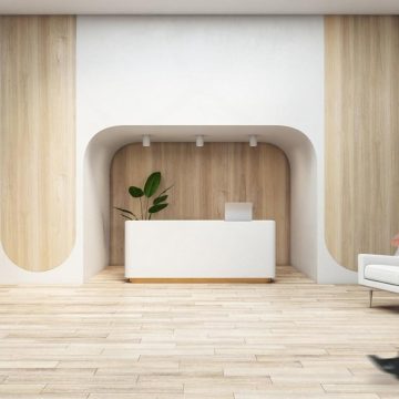 Modern minimalist lobby in the UAE with an unattended reception desk and a guest walking past, suggesting self-service check-in