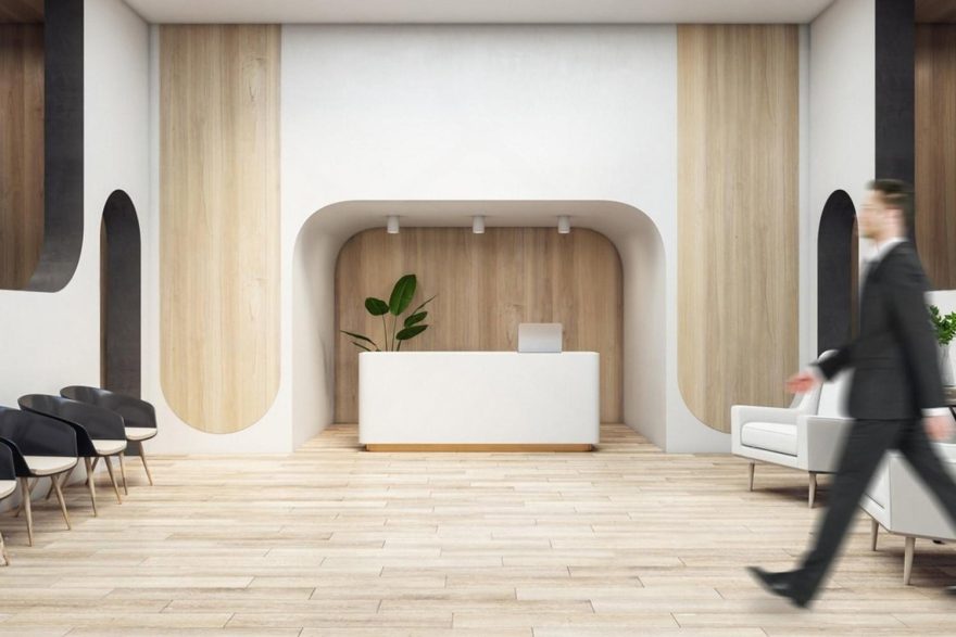 Modern minimalist lobby in the UAE with an unattended reception desk and a guest walking past, suggesting self-service check-in